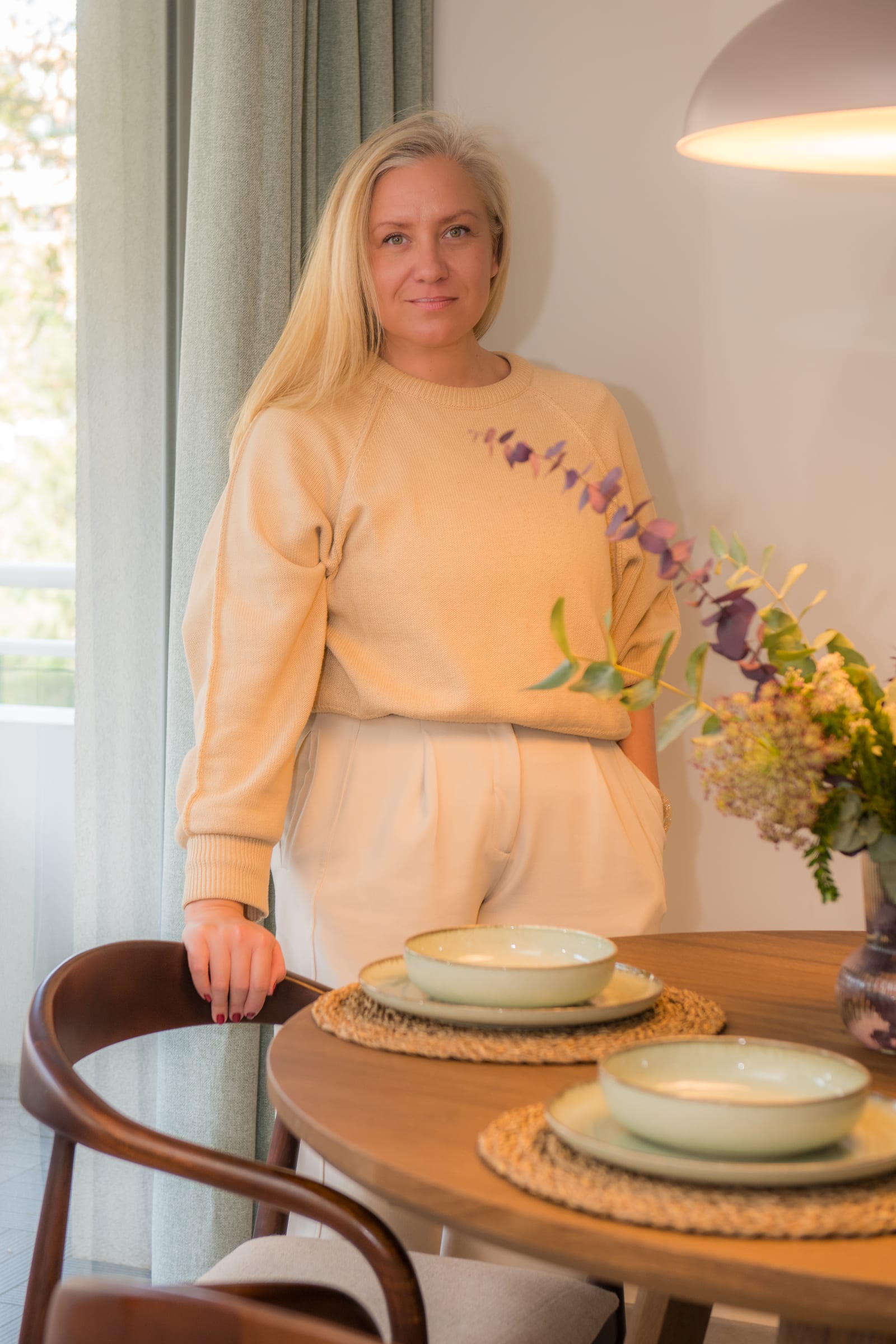 Jurgita, founder of Seijaku Studio, standing beside a table set with green ceramic bowls and dried flowers