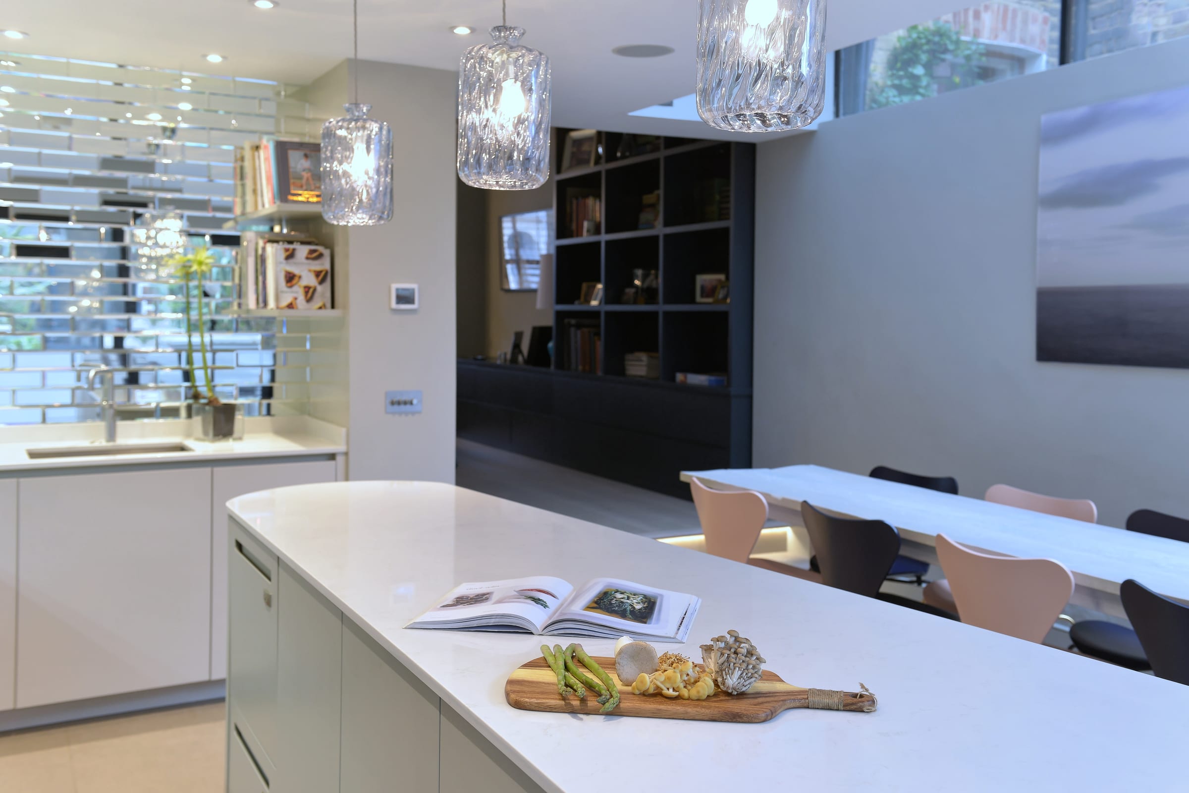 Open kitchen and dining space with a curved island and mirrored splashback