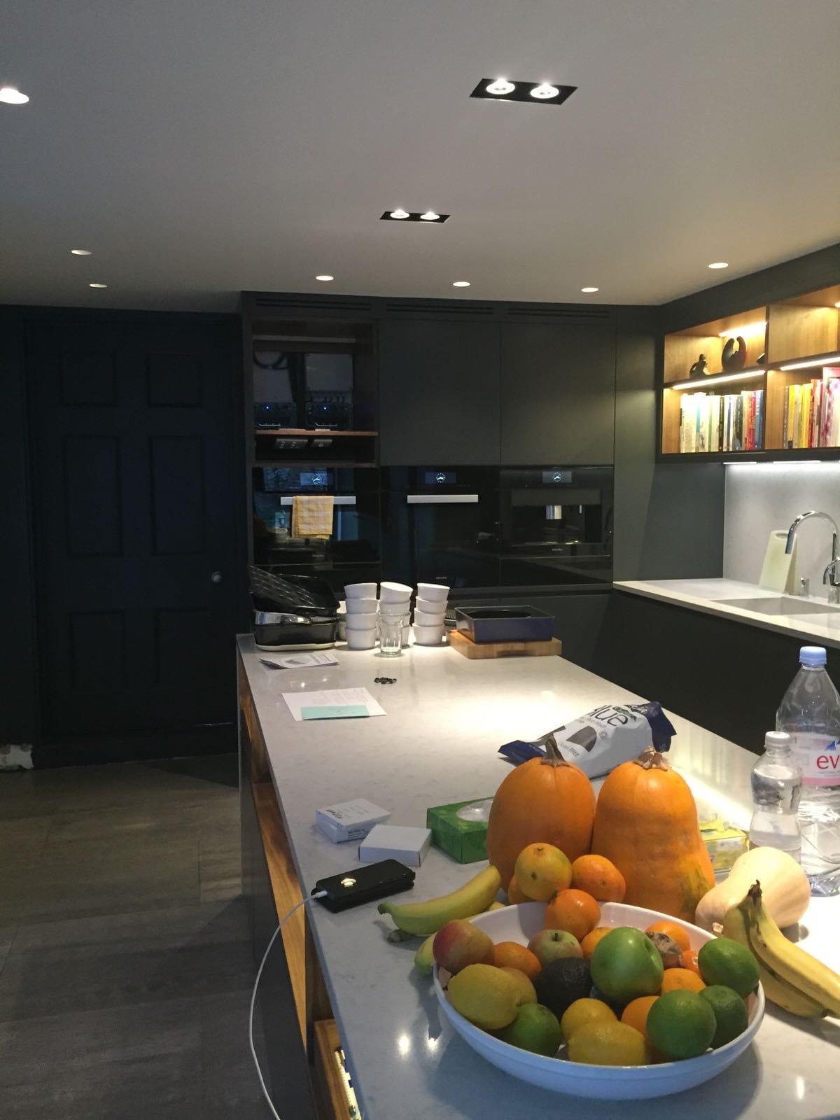 Kitchen island with a fruit bowl, under fitted spotlights and dark cabinetry