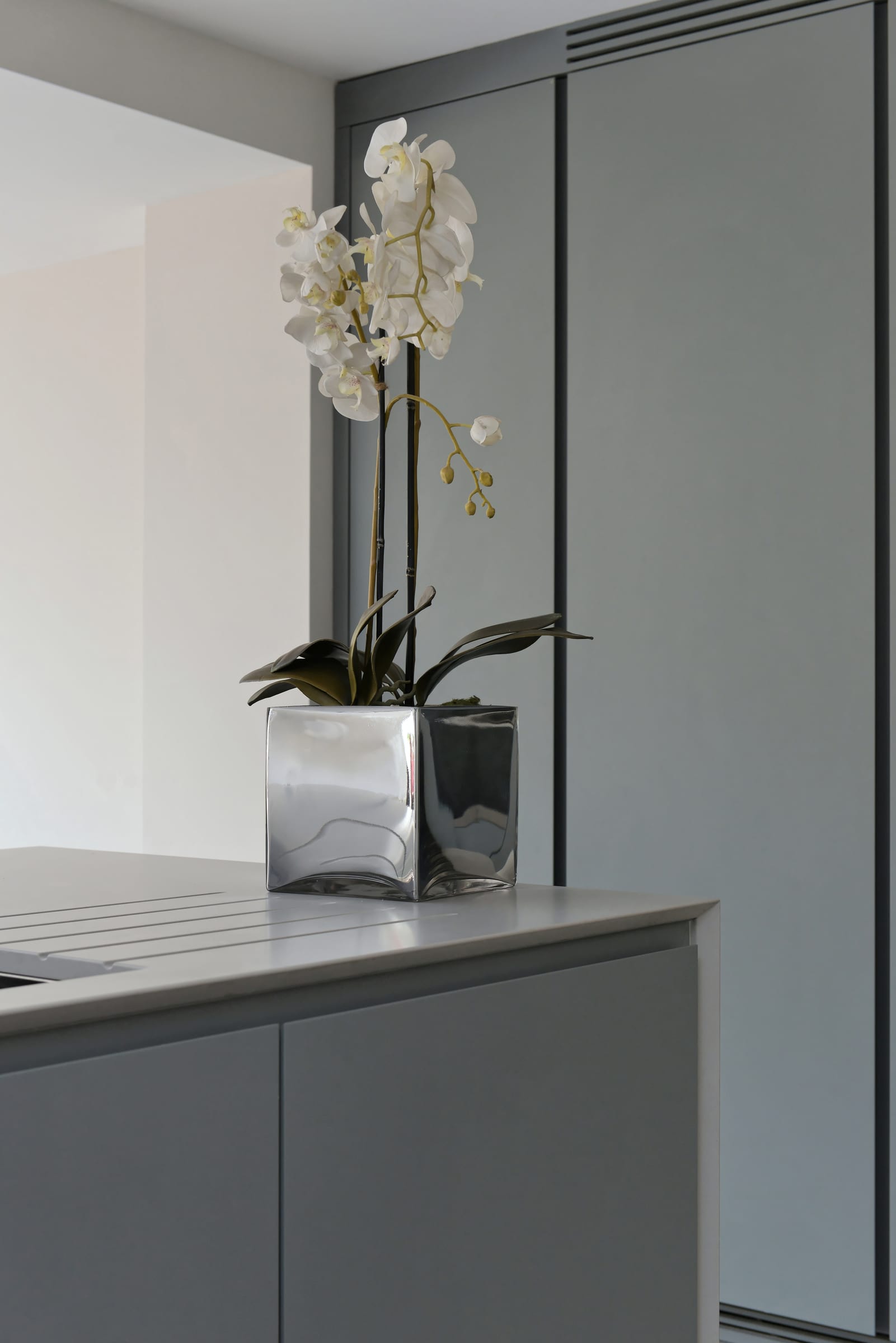 Brushed-steel mixer tap on a quartz island, with spray-lacquered grey cabinetry in the background