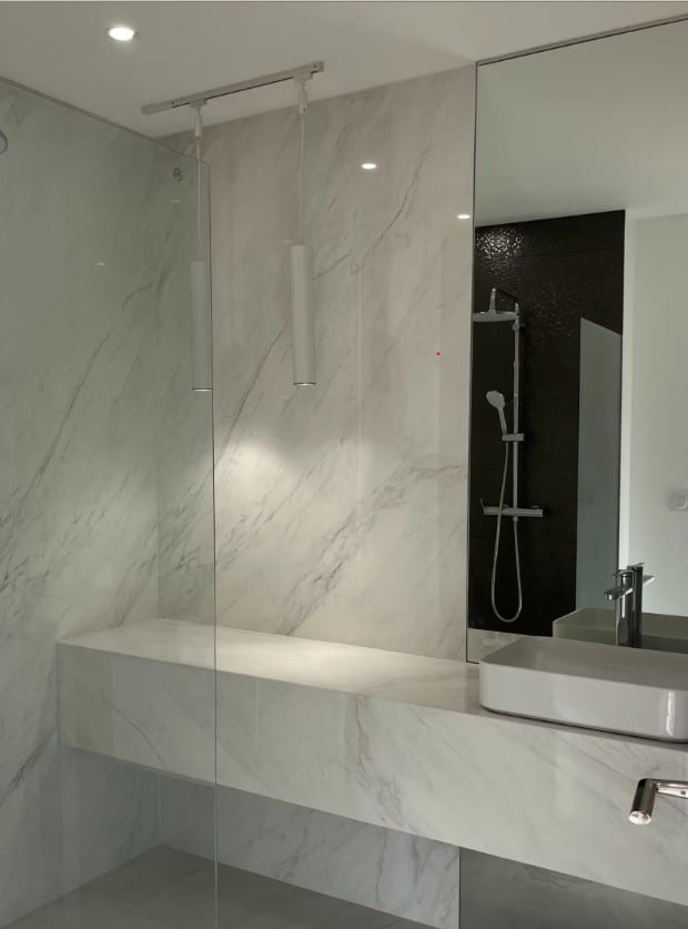 Marble spa-style bathroom at the Bellevue apartment with a walk-in glass shower and pendant lighting